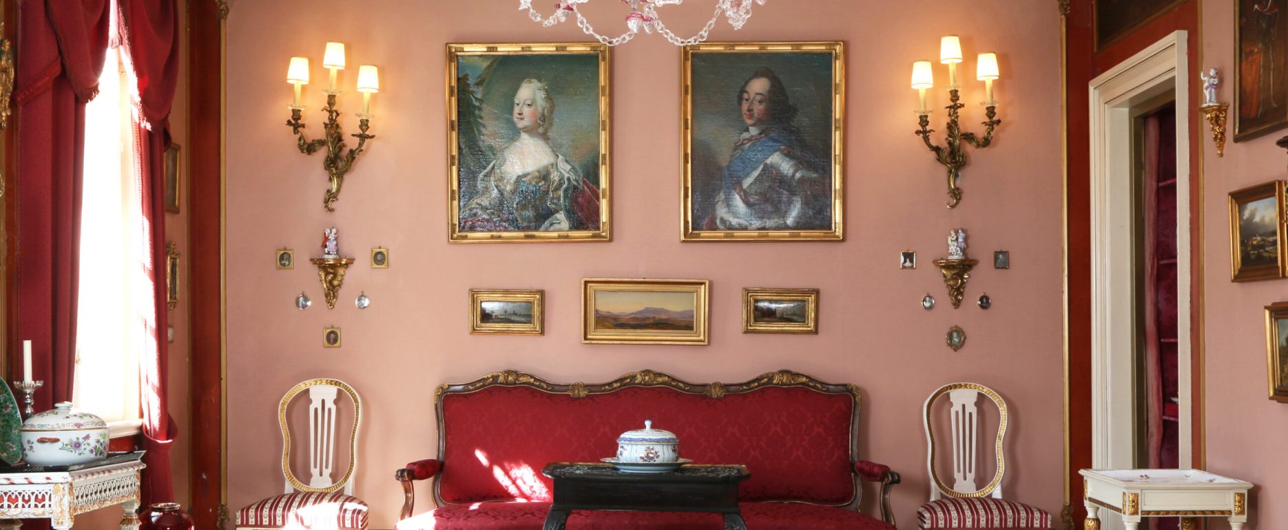 Elegant dagligstue med røde vægge og klassiske møbler